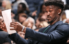 a man in a suit is holding a piece of paper in front of a crowd