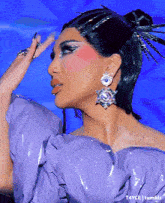 a close up of a woman wearing a purple top and earrings .