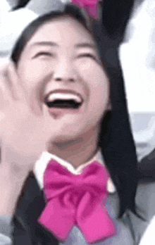 a close up of a woman wearing a pink bow tie and a cat hat laughing .