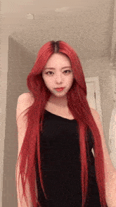 a woman with long red hair is standing in front of a mirror wearing a black tank top .
