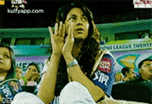 a woman sitting in a stadium with a sign that says lions league twenty in the background