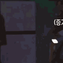 a man in a black tank top is standing in a dark room .