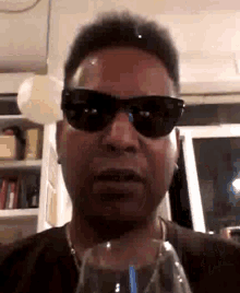 a man wearing sunglasses is holding a glass of water