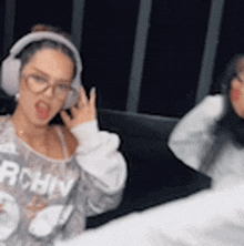 a woman wearing headphones is talking on a cell phone next to another woman wearing glasses .