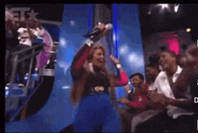a woman singing into a microphone in front of a crowd with the word bet on the bottom right