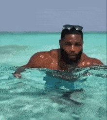 a man is swimming in the ocean without a shirt on .