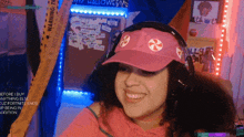 a woman wearing a pink hat and headphones is smiling in front of a sign that says halloween