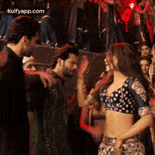 a woman in a crop top is dancing with a man in a crowd .