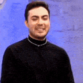 a man in a black shirt is making a funny face while pointing at the camera .