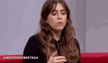 a young woman is sitting on a red couch talking to someone .