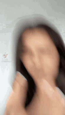 a blurry picture of a woman 's face with a tiktok logo on the bottom