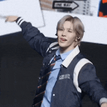 a man wearing a blue shirt and tie is standing with his arms outstretched and pointing .