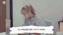 a girl with blonde hair is sitting at a table with a sign that says twice beauty tv