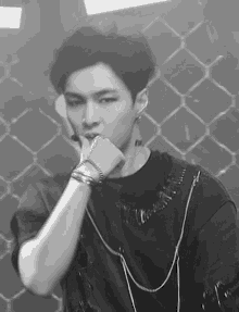 a black and white photo of a young man wearing a black shirt and bracelets .