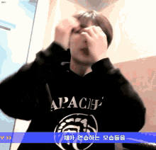 a person wearing a black apache sweatshirt covering their face