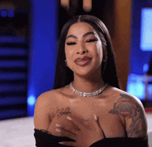 a woman with a tattoo on her arm is wearing a necklace and smiling