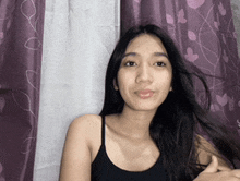 a woman with long hair is standing in front of a purple curtain