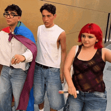 a woman with red hair is standing next to a man and a woman