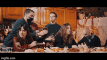 a group of people are gathered around a table with images.com written on the bottom