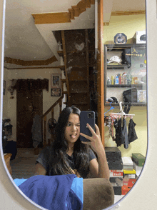 a woman taking a picture of herself in a mirror with a hat on the wall that says ' mlb ' on it