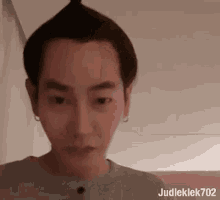 a man with a bun on his head is making a funny face while looking at the camera .