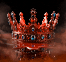 a red crown with blue and red stones on a black background