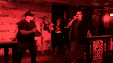 a man is singing into a microphone in a dark room with a tiger logo on the wall behind him