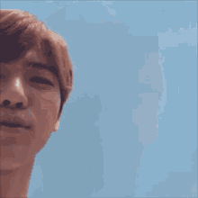 a close up of a young man 's face with a blue sky in the background .
