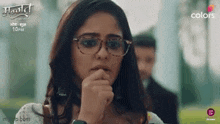 a woman is wearing glasses and covering her mouth with her hand .