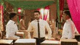 a man in a white shirt and black tie is standing in a room with other men