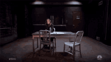 a woman sits at a table in a dark room with the hashtag #svu on the bottom