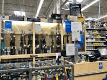 a store filled with lots of guns on shelves and a counter .