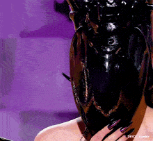 a woman with long black nails is wearing a black mask with gold horns