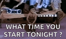 a man is sitting on a bed with the words `` what time you start tonight ? '' written on it .
