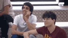 a couple of young men are sitting next to each other on a couch .
