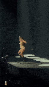 a woman is dancing on a stage with her arms outstretched in the dark