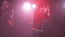 a man is singing into a microphone while another man plays a guitar