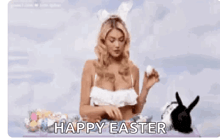 a woman in a bikini with bunny ears is sitting at a table with easter eggs and a bunny .