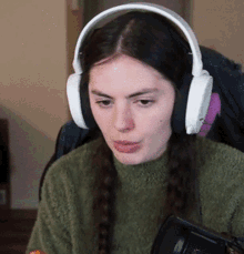 a woman wearing headphones and a green sweater is sitting in front of a microphone