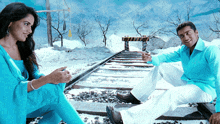 a man and a woman are sitting on train tracks