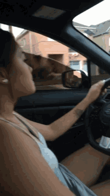 a woman is driving a car in front of a building with a red arrow on it