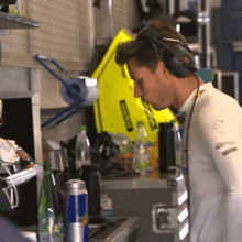 a man wearing headphones looks at a red bull can on a counter