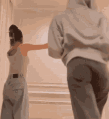 a man and a woman are standing next to each other in a room with their arms outstretched .