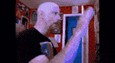 a bald man with a beard is standing in front of a red wall