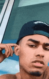 a man wearing a baseball cap is covering his ears with his hand .