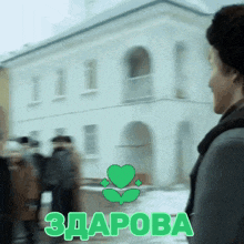 a man walking in front of a building with a green heart and the word zdrava