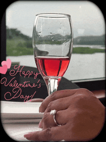 a woman holding a glass of wine with the words happy valentine 's day written in pink