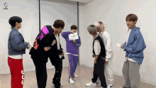 a group of young men are standing in a room and one of them has a sign on his back that says ' x '