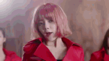 a woman with pink hair is wearing a red jacket and making a face .