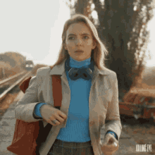 a woman wearing a blue sweater and a bow tie is walking down a street .